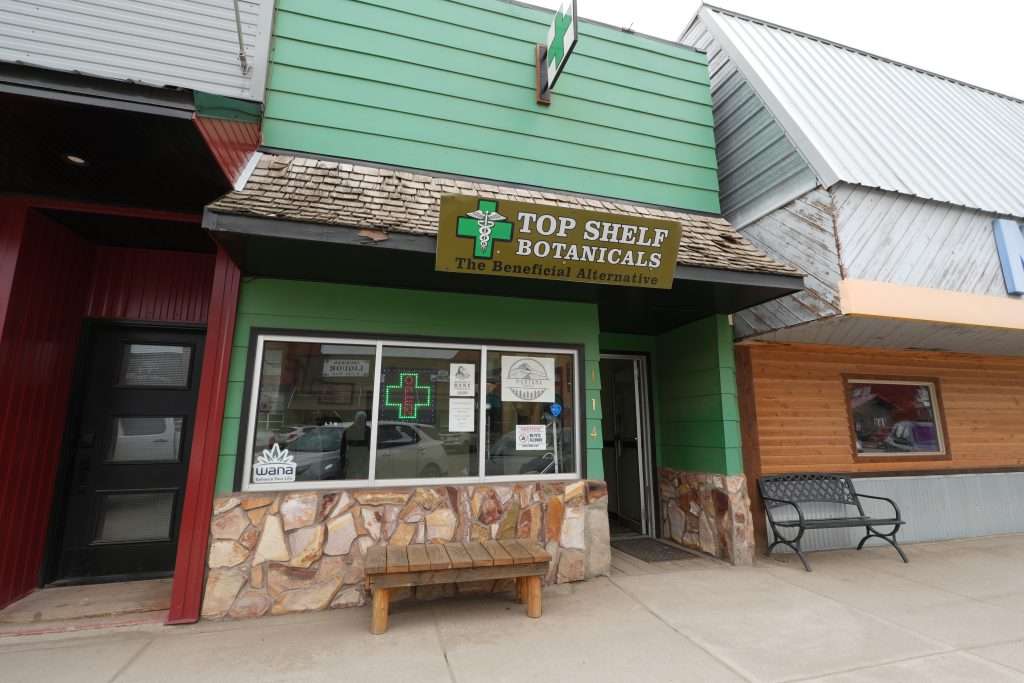 Exterior of Sheridan dispensary, MT, with cannabis signage and parking area.