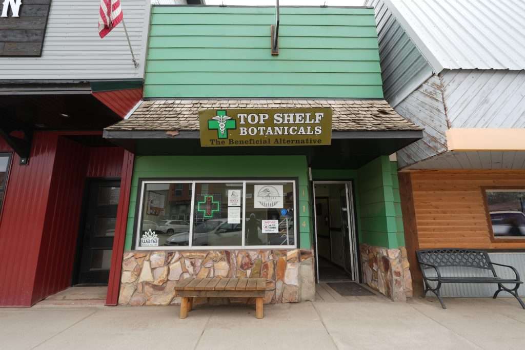 Exterior of Sheridan dispensary, MT, with cannabis signage and parking area.