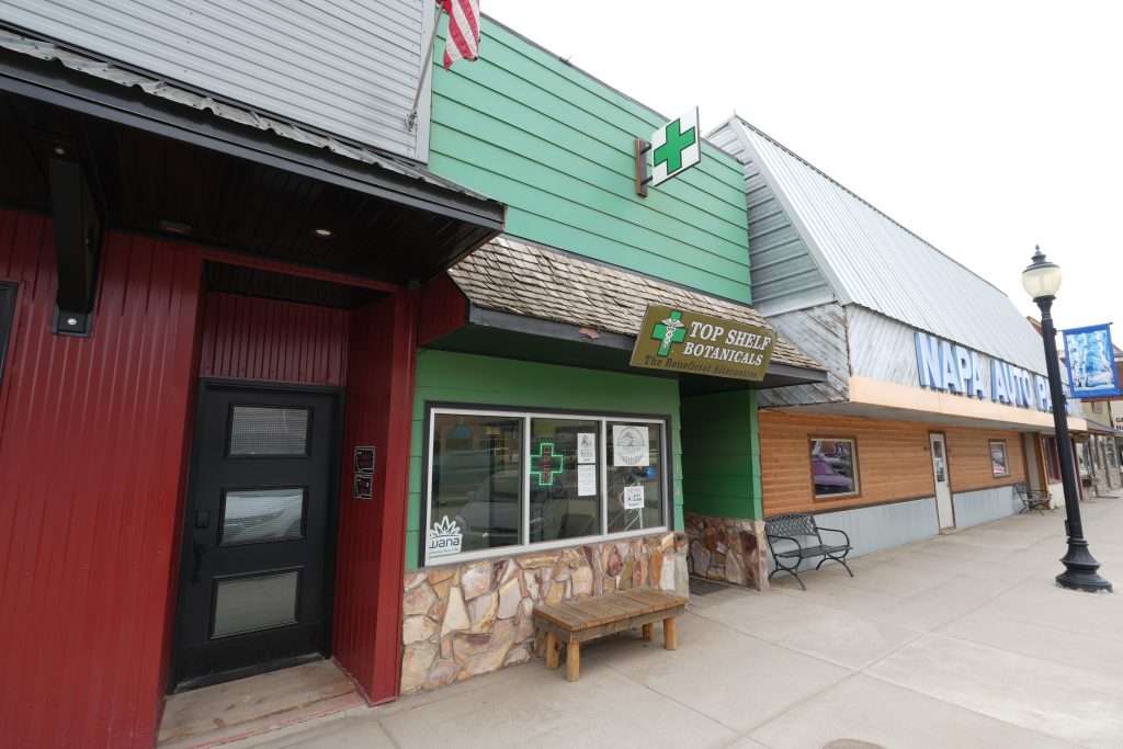 Exterior of Sheridan dispensary, MT, with cannabis signage and parking area.