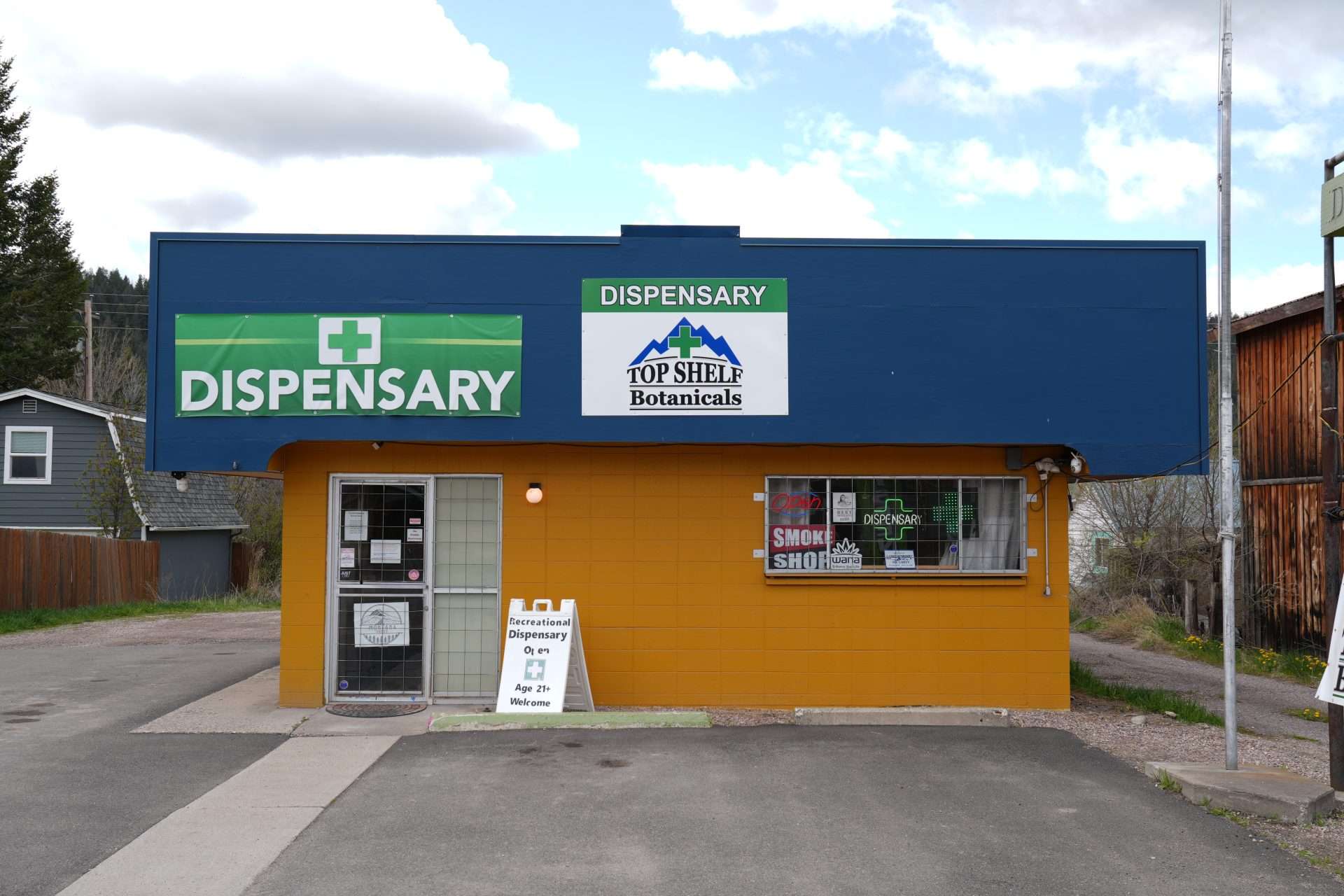 Exterior of Arlee dispensary, MT, with cannabis signage and parking area.